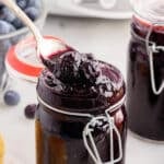 A mason jar filled with Blueberry Butter, a spoon lifting some out.