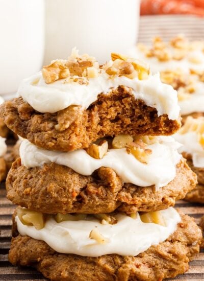 Carrot Cake Cookies with frosting on top and a bite out of the top cookie.