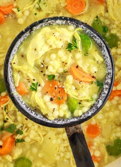 Top close up of a ladle full of chicken couscous soup.
