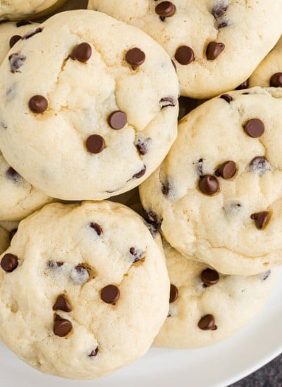 White serving plate with chocolate chip cheesecake cookies piled.