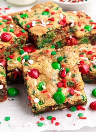 Christmas bar cookie squares set out on parchment paper with red and green M&Ms.