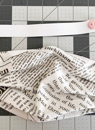 newsprint patterned face mask and white elastic band with pink buttons