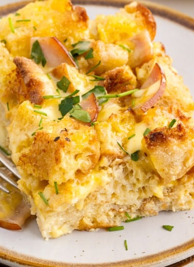A slice of Eggs Benedict Casserole on a small dish with a fork.