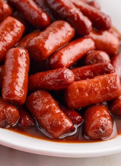 Close up of crockpot grape jelly smokies on a white plate.