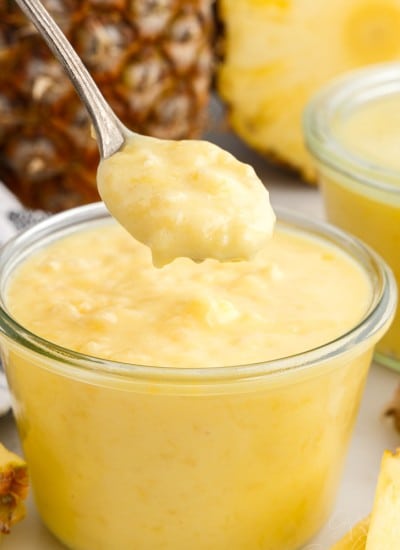 Pineapple Curd in a small glass dish and a spoonful lifted from it.