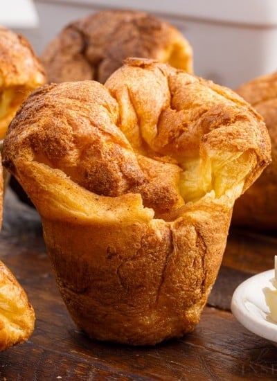 Close up of popovers on a cutting board next to butter.