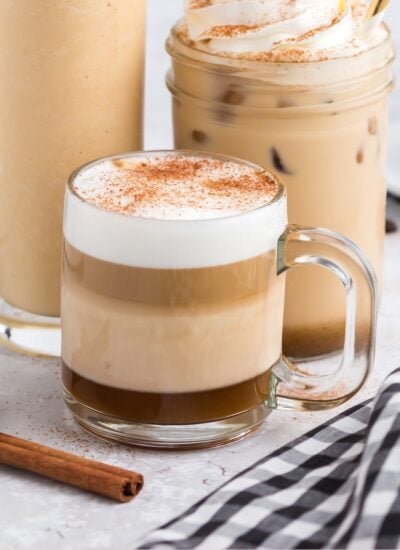 Three different sized glasses with pumpkin spice lattes; hot, on ice, and blended, with whipped cream.