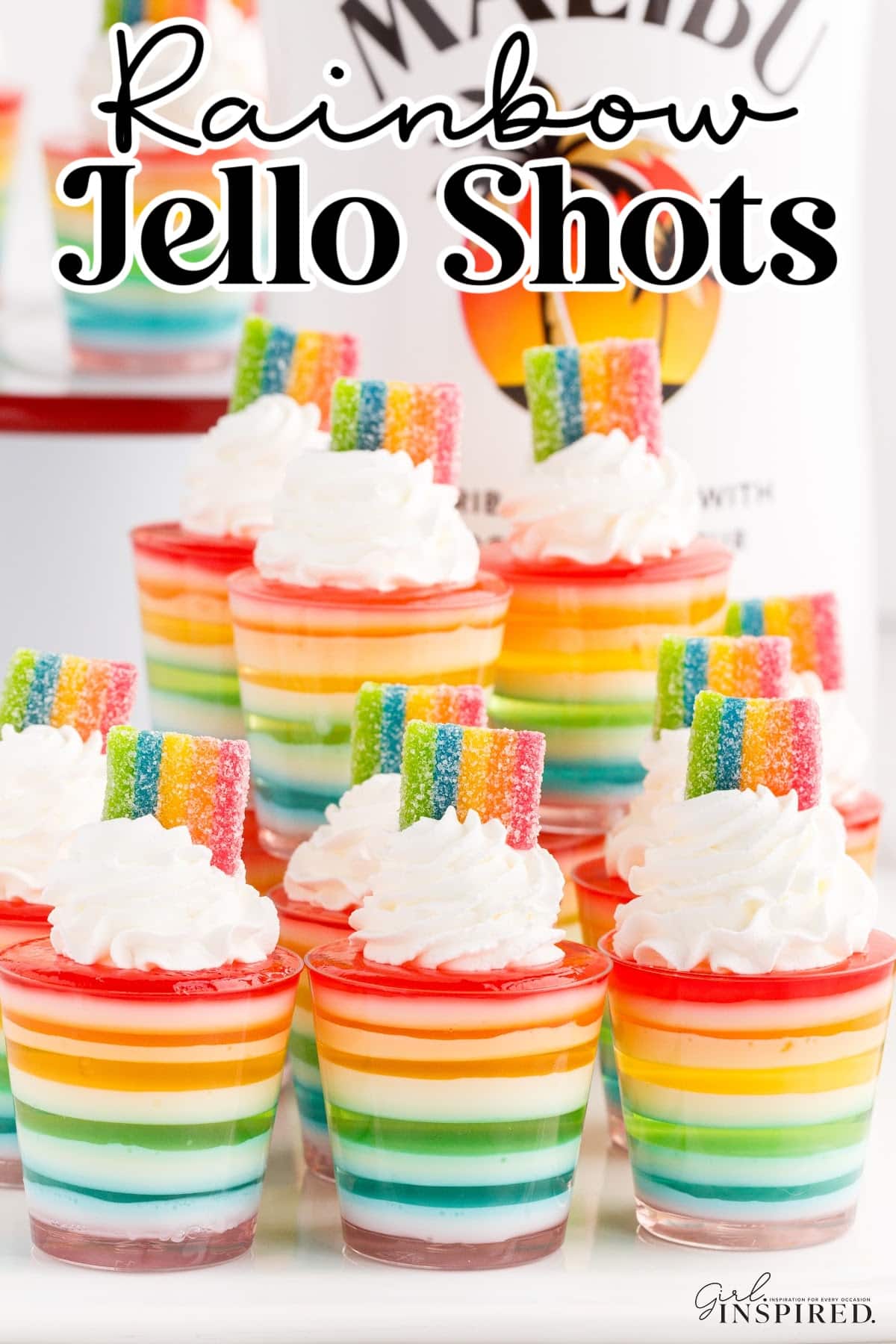 Rainbow Jello Shots with whipped cream and rainbow candies as garnish.