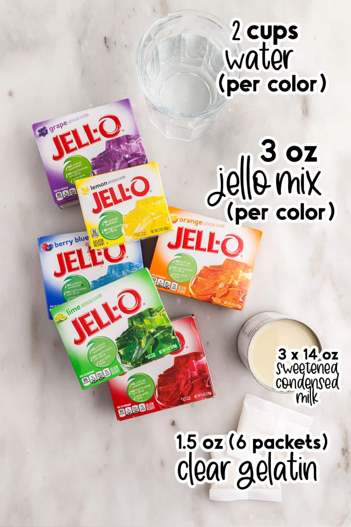 Rainbow layered jello ingredients gathered on a marble countertop.