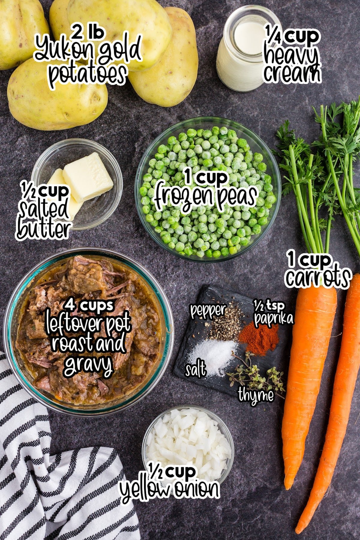 Ingredients used to make Shepherd's pie with leftover roast beef, striped kitchen cloth alongside the ingredients on a dark marble countertop.