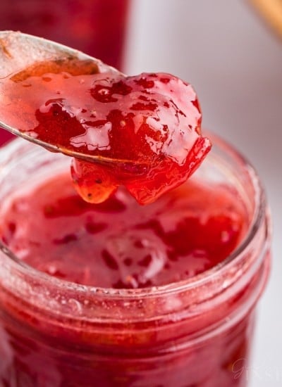 Spoonful of strawberry rhubarb jam lifted from jam jar.